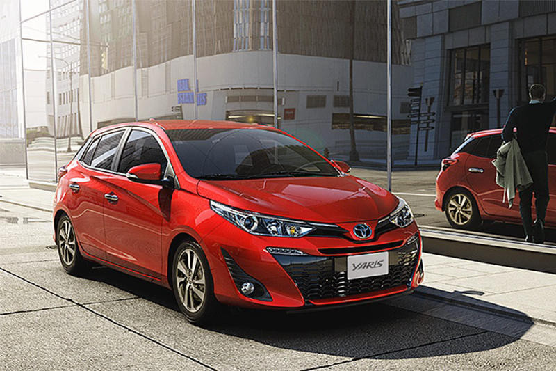 Một chiếc Toyota Yaris màu đỏ đỗ cạnh tòa nhà