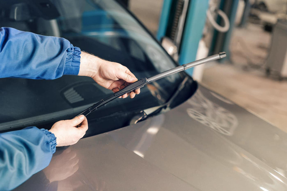 Người chủ xe đang tự tay thay cần gạt nước kính chắn gió ô tô