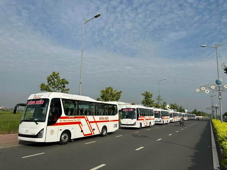 Xe khách Hùng Hiếu đang di chuyển trên đường, nổi bật với logo và màu sắc đặc trưng